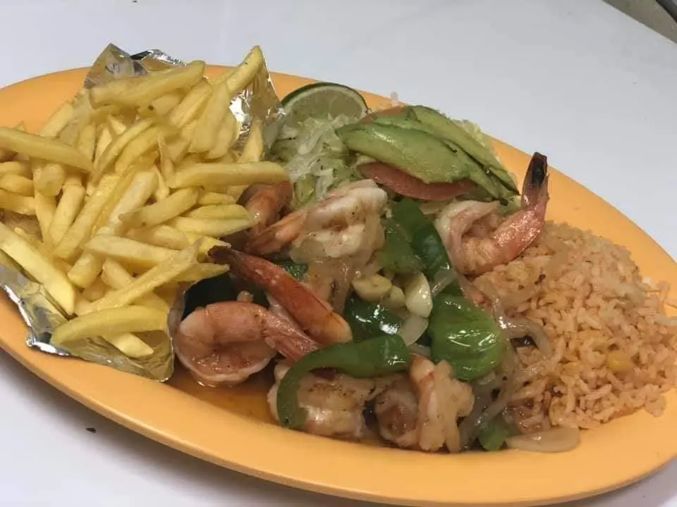 Plate of shrimp with green peppers and onions, served with french fries and rice