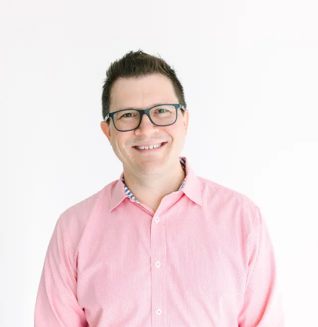 Headshot of a man in a pink button down shirt with a collar