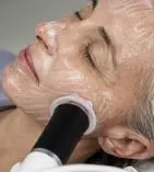 Person receiving a facial treatment with a handheld device applied to their cheek