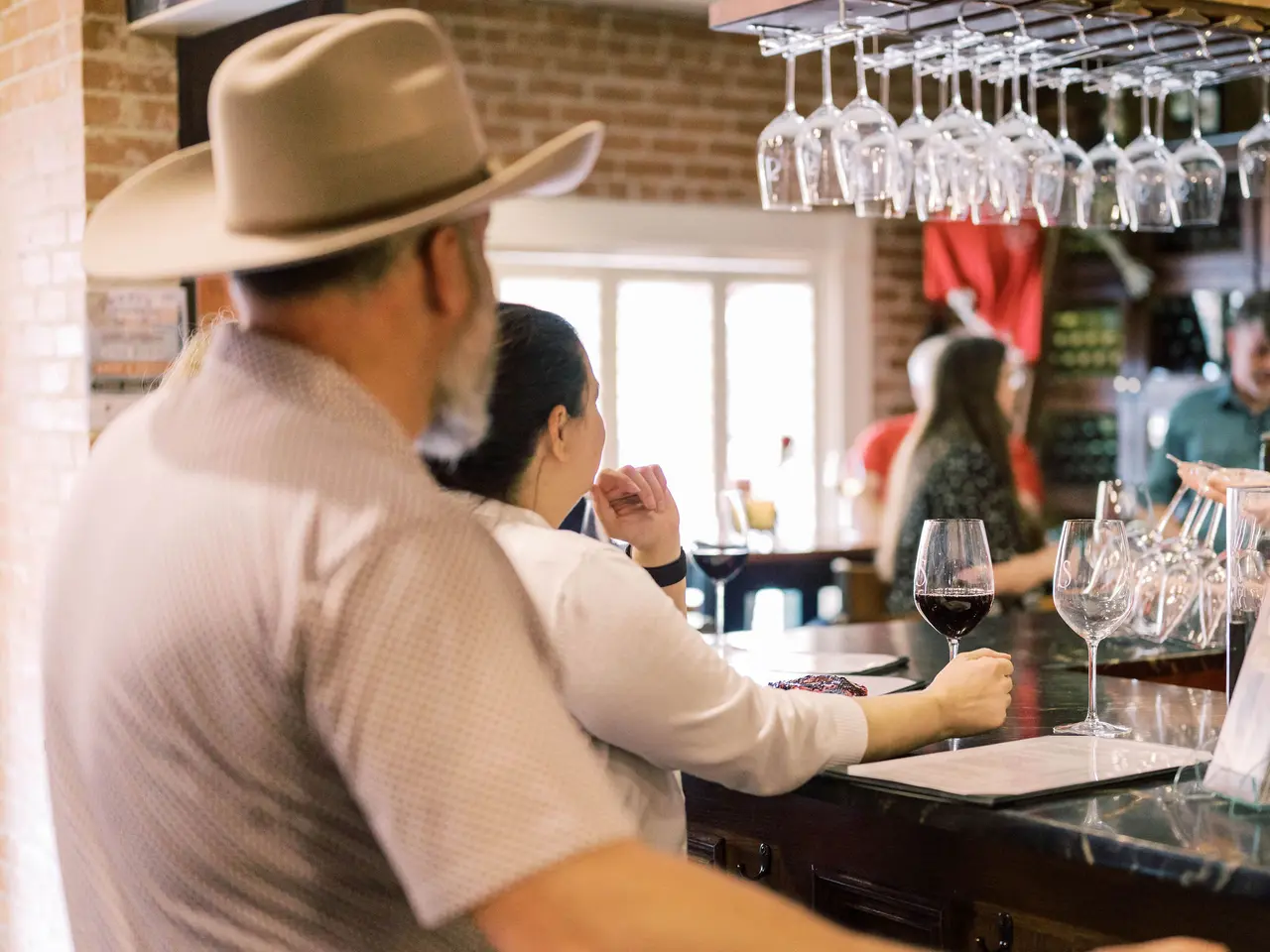 Man and woman sitting at a bar top drinking a glass of wine