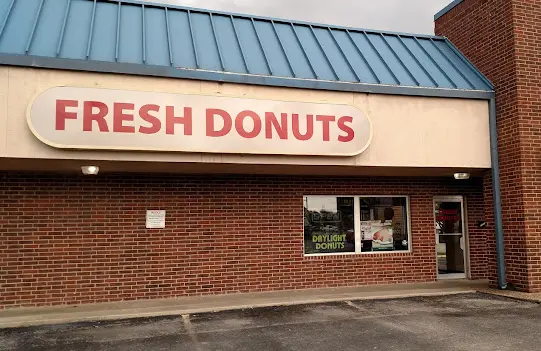 Brick storefront with metal roof awning displaying "FRESH DONUTS" sign and glass entrance door