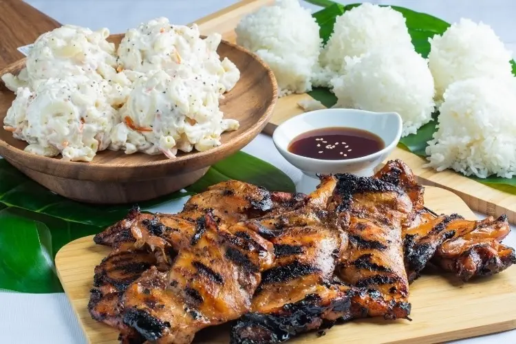 Grilled meat skewers with char marks served alongside shredded white salad and steamed white rice with dipping sauce