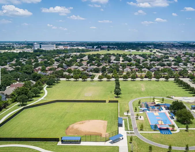 Aerial view of a 10-acre park with baseball diamond, sports courts, walking trail, and surrounding residential neighborhood