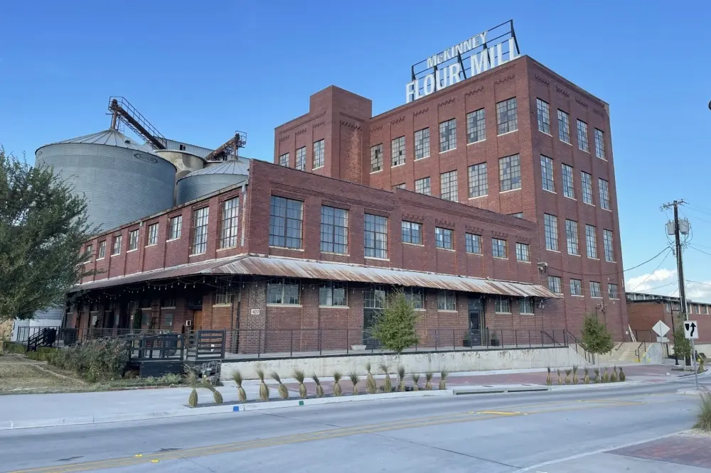 Historic red brick flour mill building with grain elevator and loading dock, clear blue sky behind