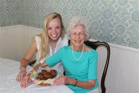 Two women smiling at a table with pastries and tea service between them