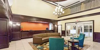 Hotel lobby with seating area, teal armchair, chandelier, and reception desk with orange backdrop