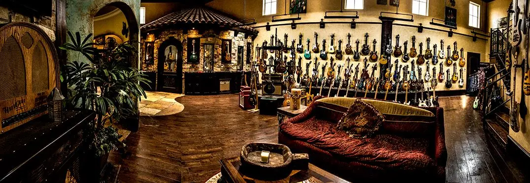 Interior of guitar shop with wooden floor, burgundy seating, display shelves of guitars, and wooden barrel on left side