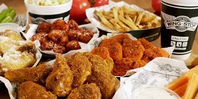 Fried chicken wings, french fries, popcorn, and soft drinks arranged on a table with a receipt