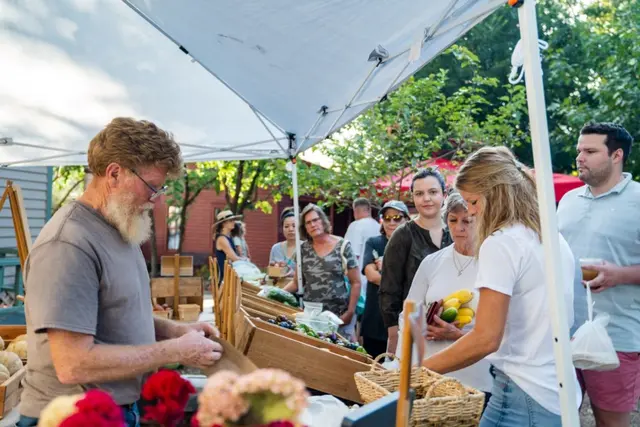 People shopping from a farm stand at a farmers market