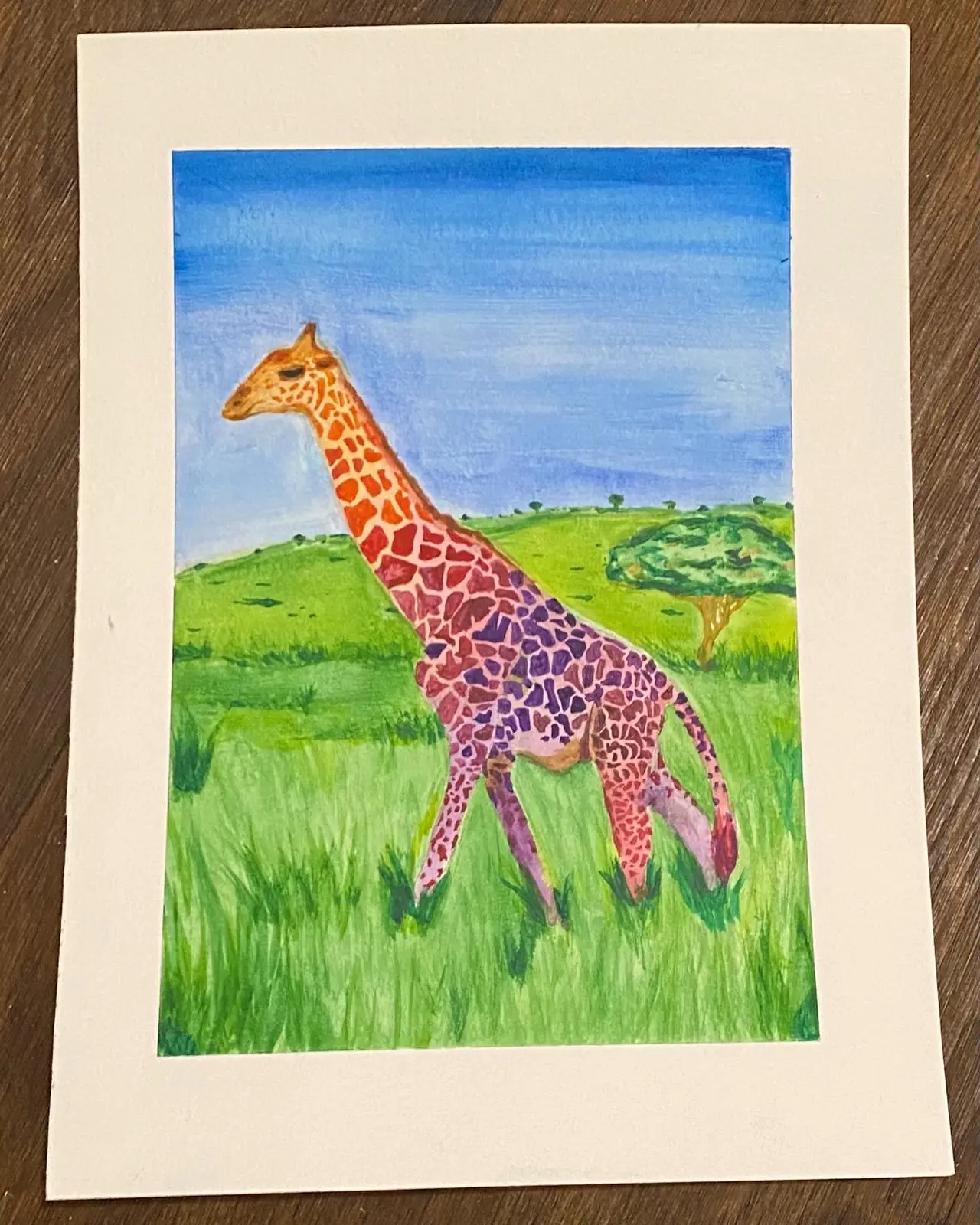 Painted giraffe with orange and purple patterned coat walking through green grassland under blue sky