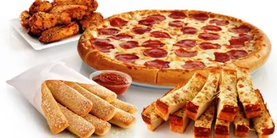 Pepperoni pizza, chicken wings, breadsticks, and cheese-filled crust pieces arranged on white surface