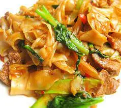 Stir-fried noodles with meat and green onions on a white plate