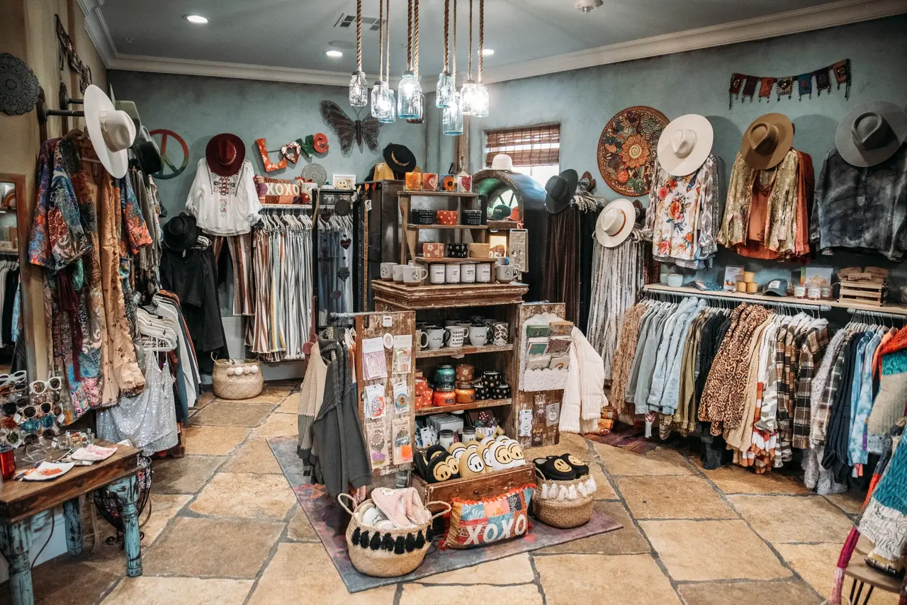 Boutique interior with clothing racks, hats, and decorative accessories displayed on walls and shelves throughout the space