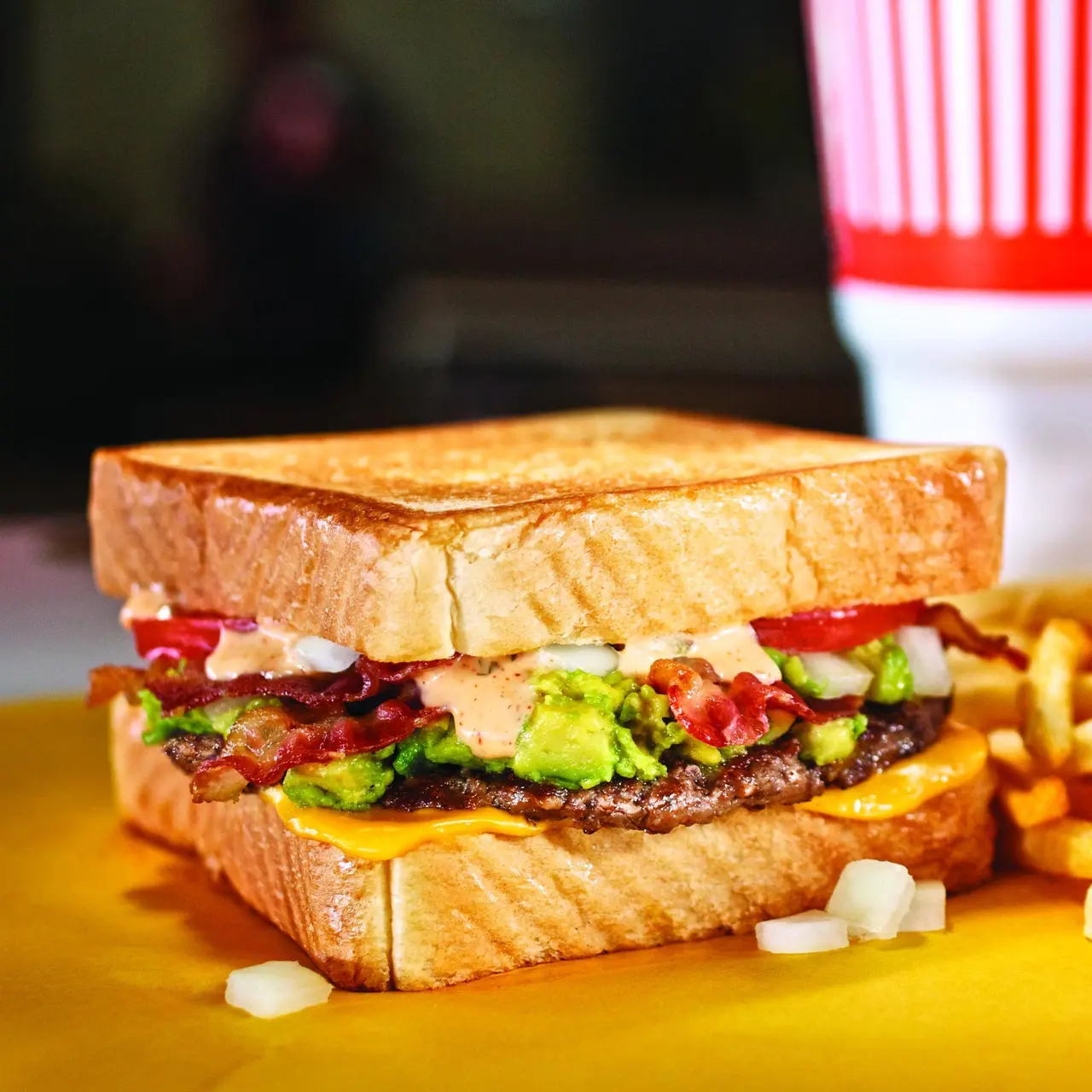 Toasted sandwich with beef patty, bacon, lettuce, tomato, and green peppers, served with french fries
