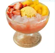 Chilled fruit tea in a glass bowl with strawberry, mango, and lychee pieces floating on top