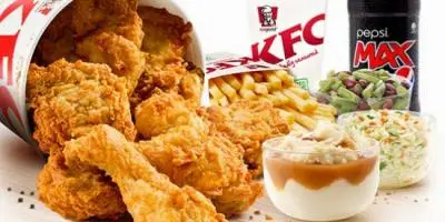 Crispy fried chicken pieces with coleslaw, fries, and a beverage on white background