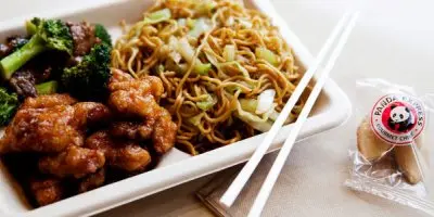 Crispy fried chicken, steamed broccoli, and crispy chow mein noodles in white bowl with chopsticks