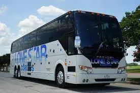 Blue and white double-decker motorcoach parked on a road with trees and sky in background