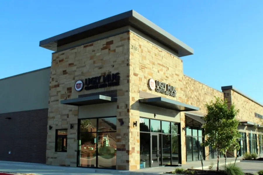 Stone and brick commercial building with large windows and glass doors under clear blue sky