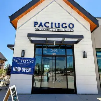 White storefront with orange roof trim and large glass doors, "Paciugo" signage above, "Now Open" sign visible on left side