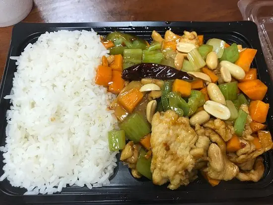 White rice beside cashew chicken with bell peppers, onions, and cashews on black compartmentalized tray