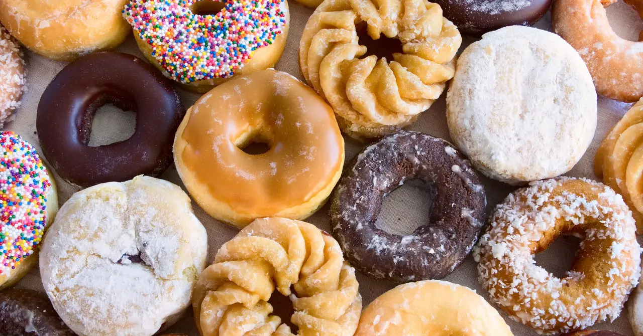 Assorted glazed, frosted, and powdered donuts in various flavors arranged closely together