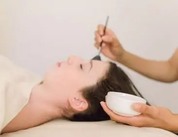 Woman receiving facial treatment with cream application at spa