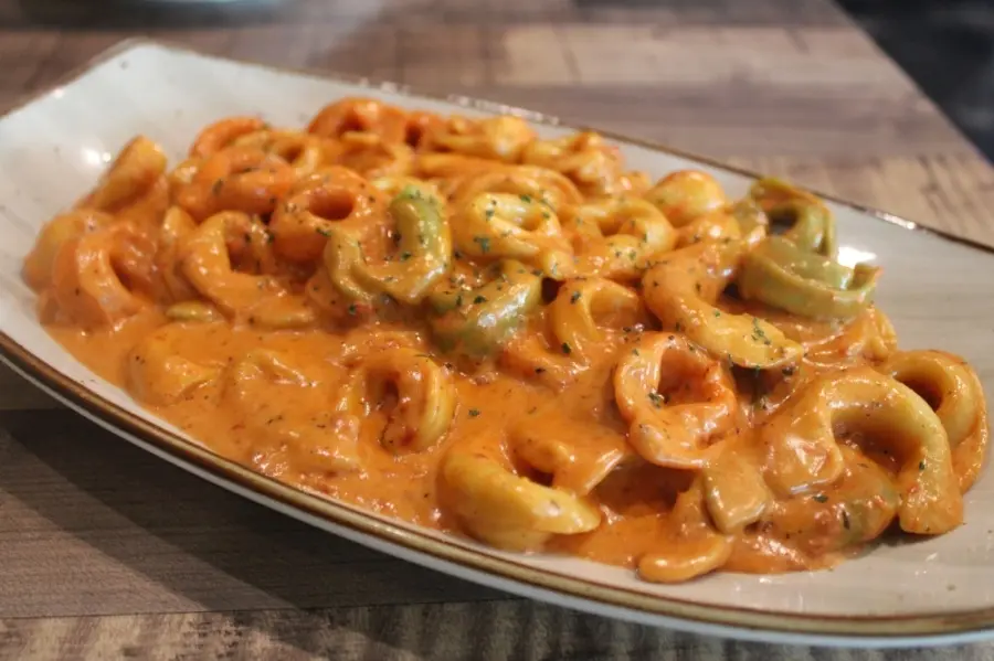 Curled pasta in creamy tomato sauce on white plate