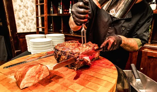 Butcher block with someone carving a steak on it