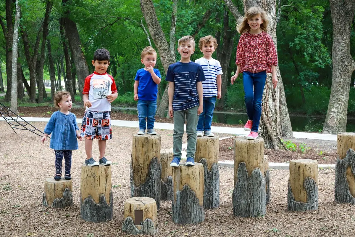 Group of kids at a playground standing on stepping stones