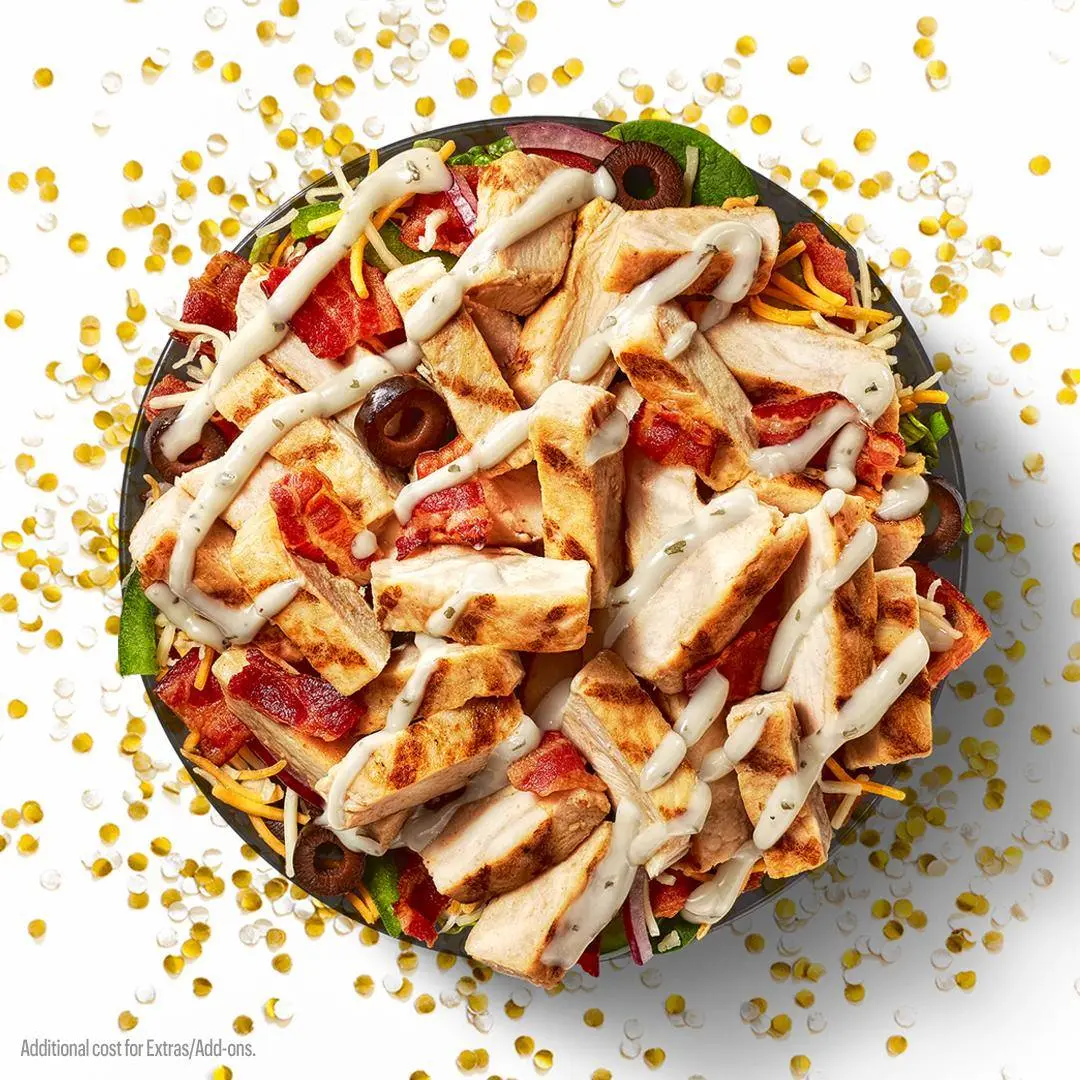 Overhead view of multiple submarine sandwiches arranged on a platter with lettuce, surrounded by scattered gold and white confetti