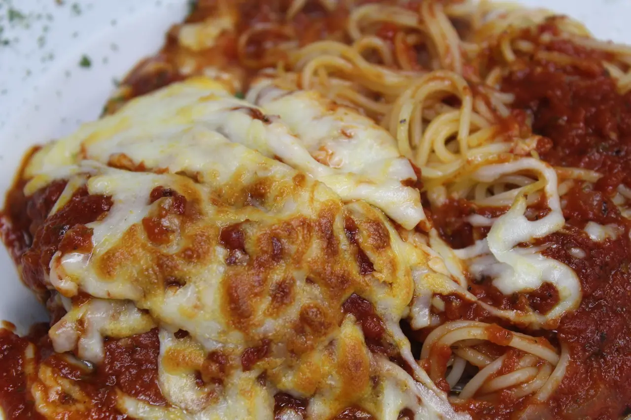 Baked pasta dish with melted cheese, tomato sauce, and curled noodles on top
