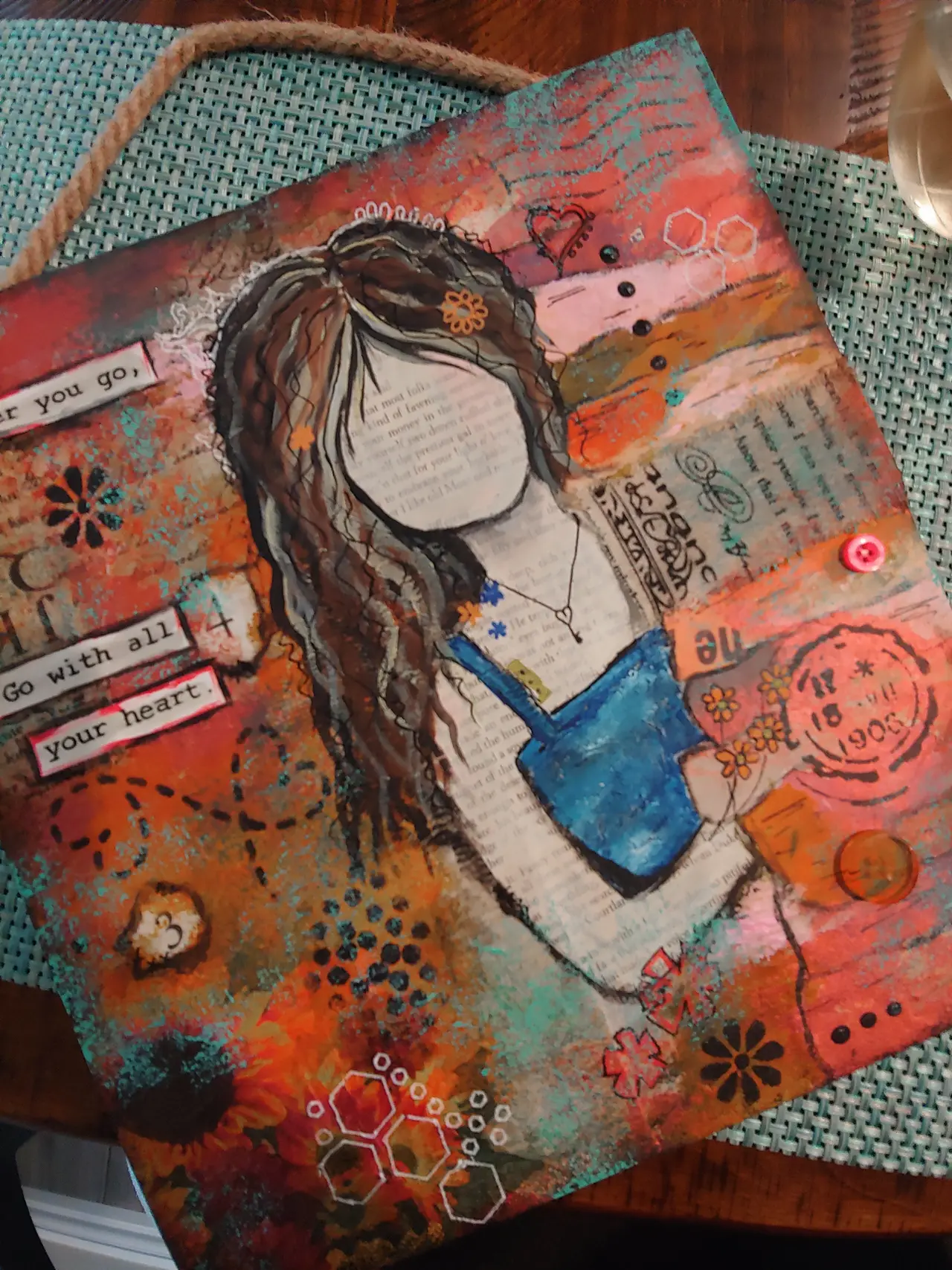 Mixed media artwork featuring illustrated figure with long brown hair wearing blue shirt, surrounded by colorful painted backgrounds, decorative stamps, and