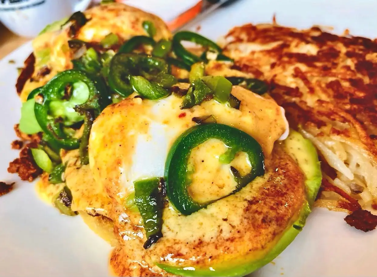 Golden-brown egg patties topped with melted cheese and sliced green jalapeños, served with hash browns