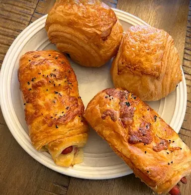 Four croisants set out on a white plate filled with cheese and sausage