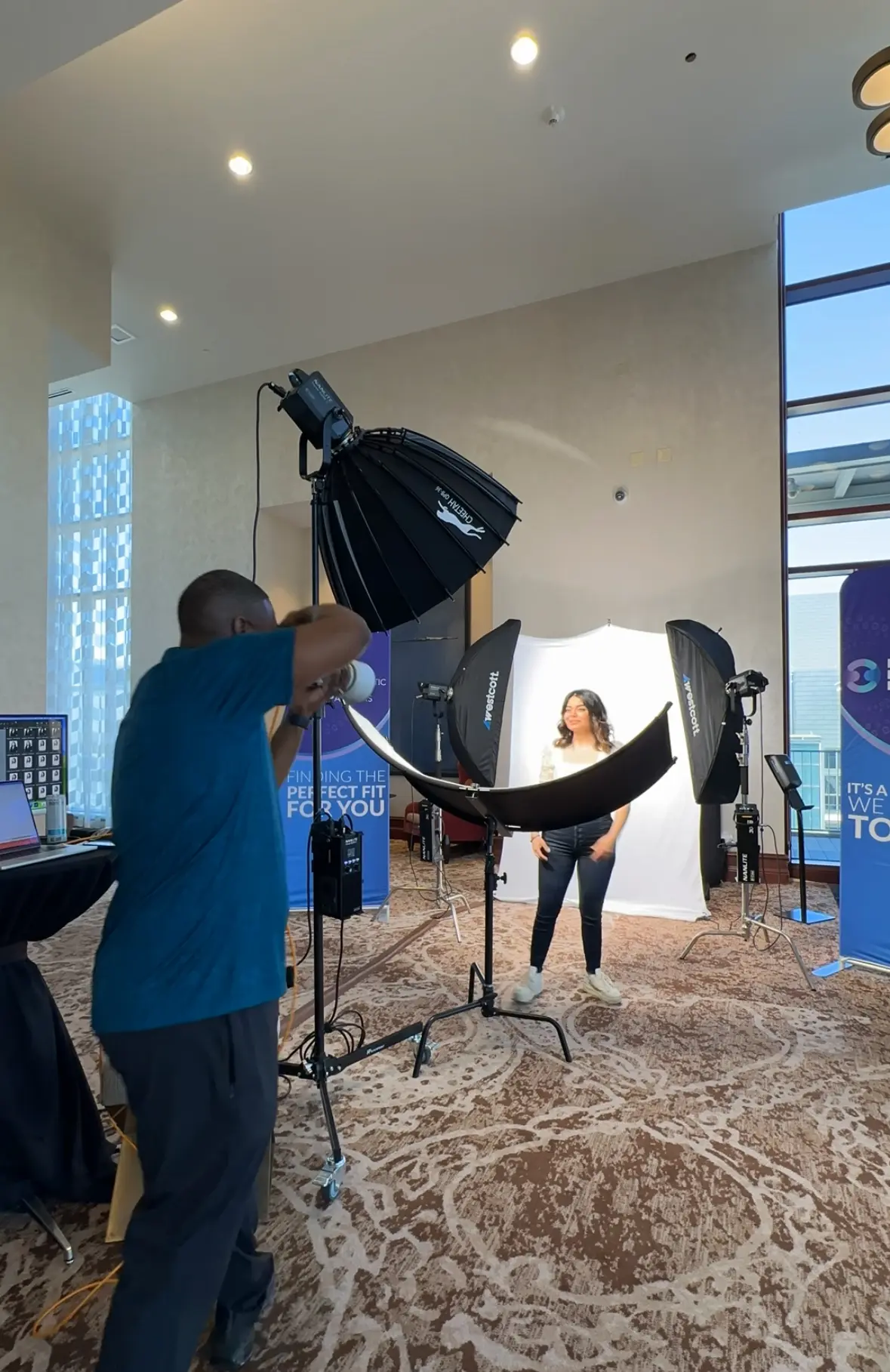 Professional photographer operating studio lighting equipment during a corporate portrait session in a modern event space
