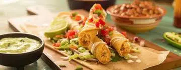 Fried rolled pastries filled with meat topped with fresh vegetables and sauce, served with dipping sauce and rice