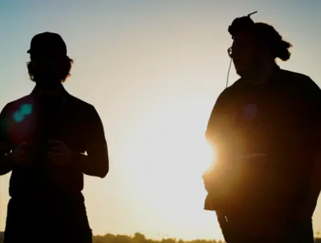 Two runners jogging together silhouetted against a bright sunset sky