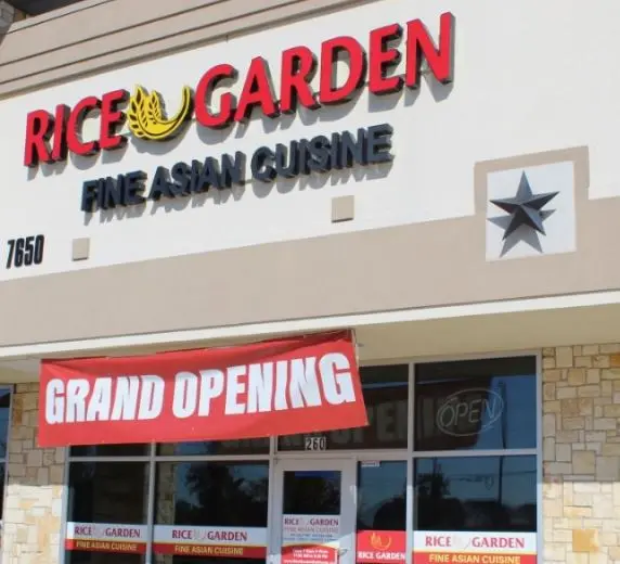 Restaurant storefront with red "Rice Garden" signage and "Grand Opening" banner across large windows