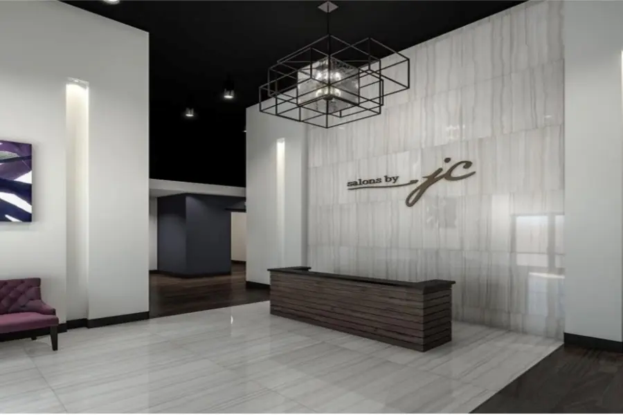 Modern salon reception area with white textured walls, geometric pendant light, dark wood reception desk, and purple seating