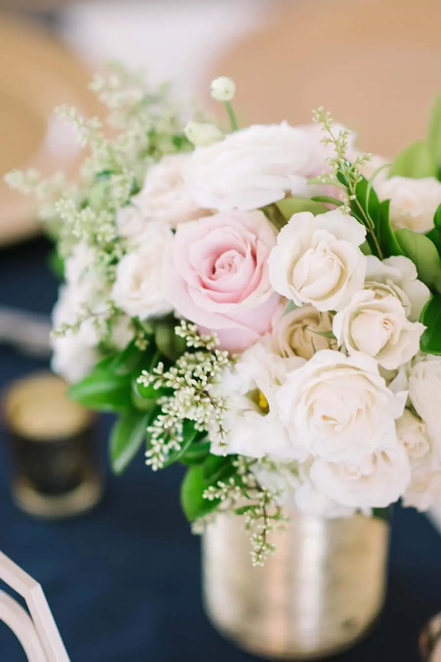 Bridal bouquet of pale pink and cream roses with white baby's breath filler flowers in a metallic vase