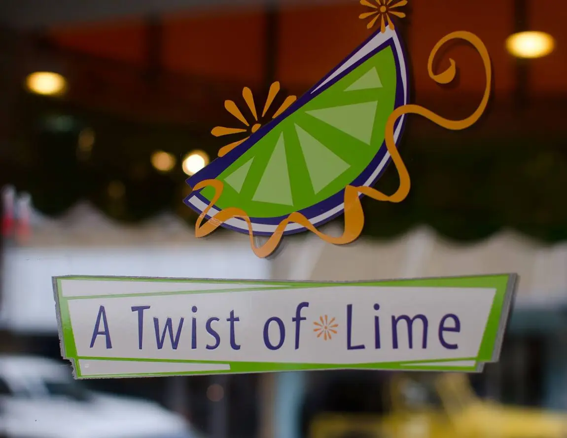 Window signage featuring a lime wedge illustration with decorative gold swirls and the business name below