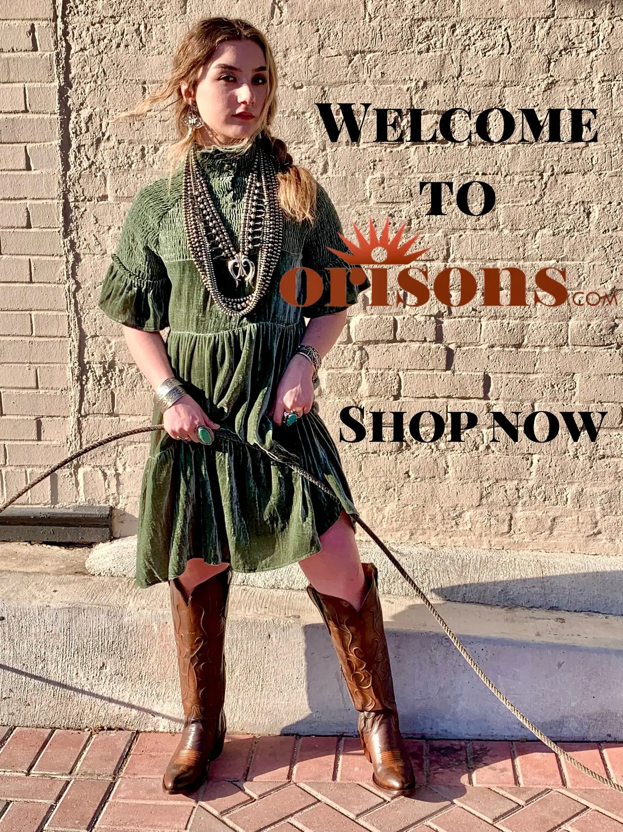Person wearing olive green dress and brown boots standing against brick wall