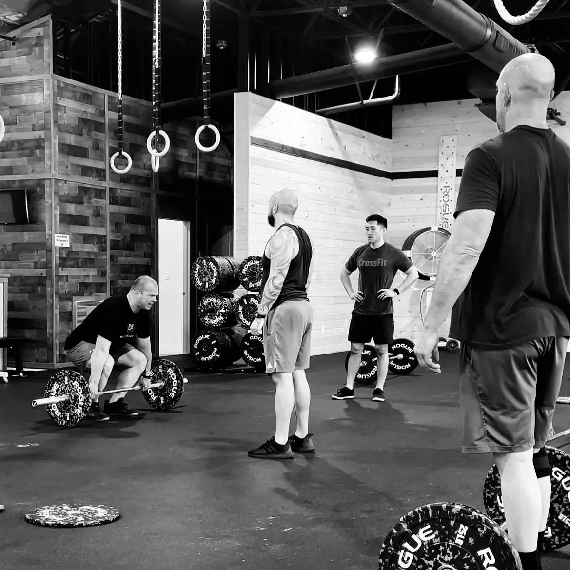 Group fitness class with participants exercising with weights and rings in modern gym facility