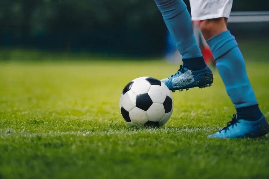 Soccer player in blue socks and cleats about to kick black and white ball on grass field