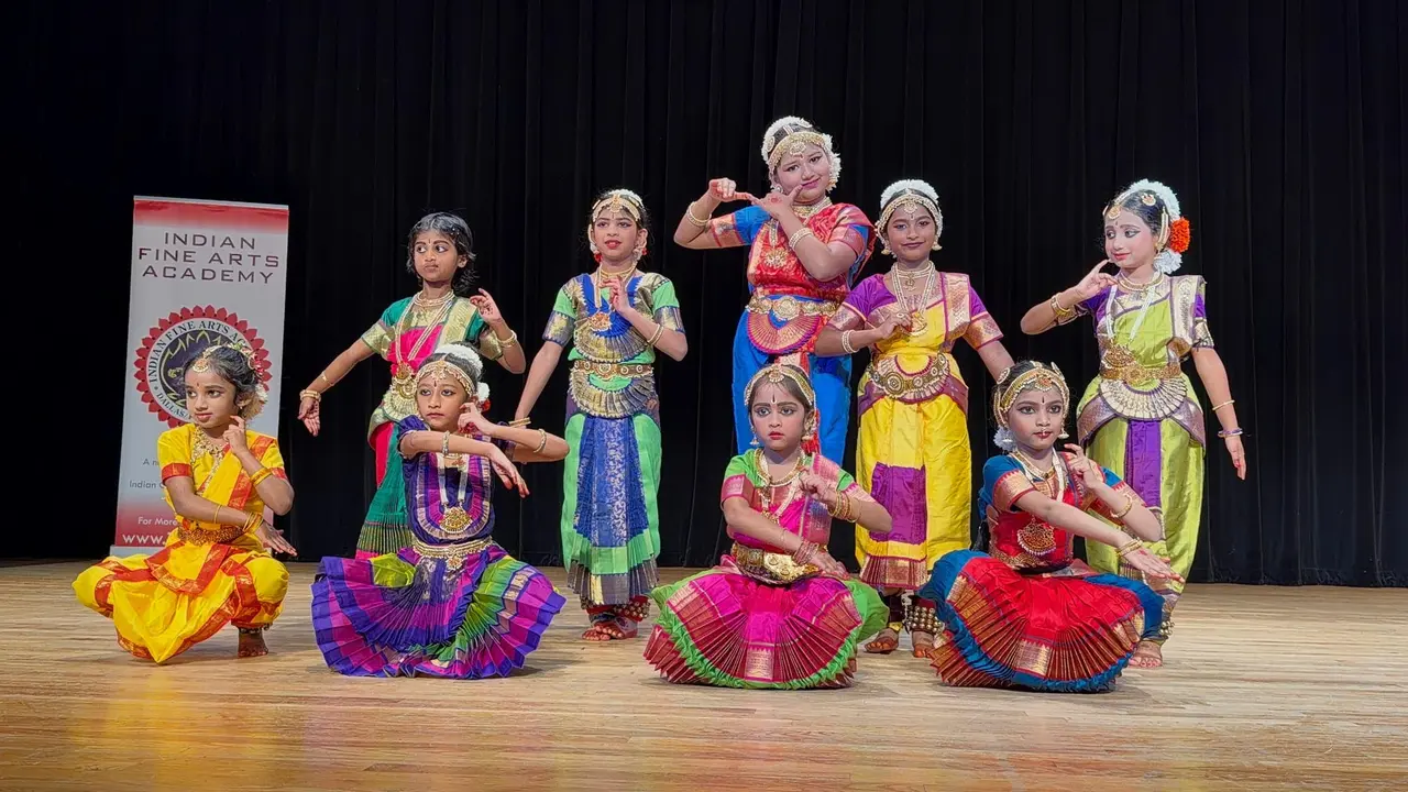 Children in colorful traditional Indian dance costumes performing on stage together