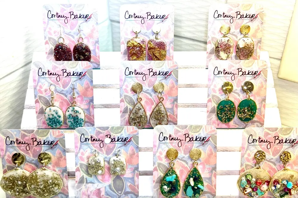 Display of resin earrings in various colors and glitter finishes on branded packaging cards