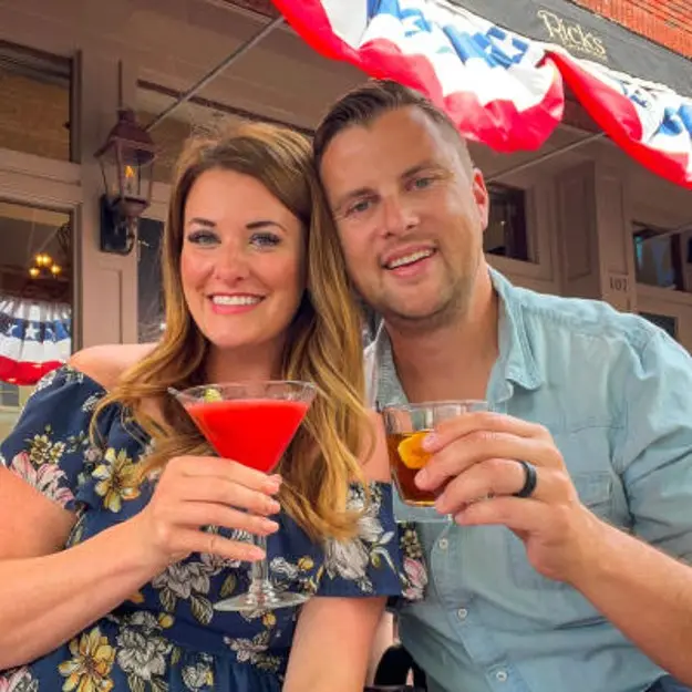 Man and woman posing with cocktails smiling at the camera