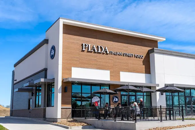 Modern restaurant building with wood and metal facade, large windows, and covered outdoor seating area