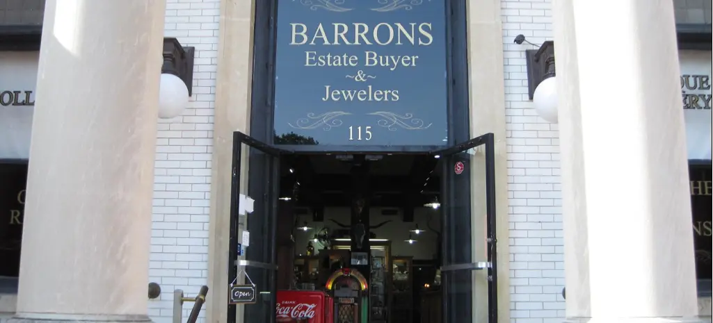 Storefront entrance with blue awning sign for jewelry store, white brick facade, and dark display windows